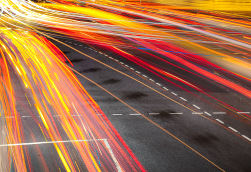 Traffic flows at night, with vehicle headlights and tail lights creating blurred lines and patterns.