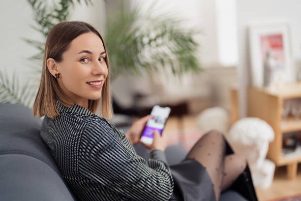 istock Woman holding phone in her hands while sitting on couch 1368641141