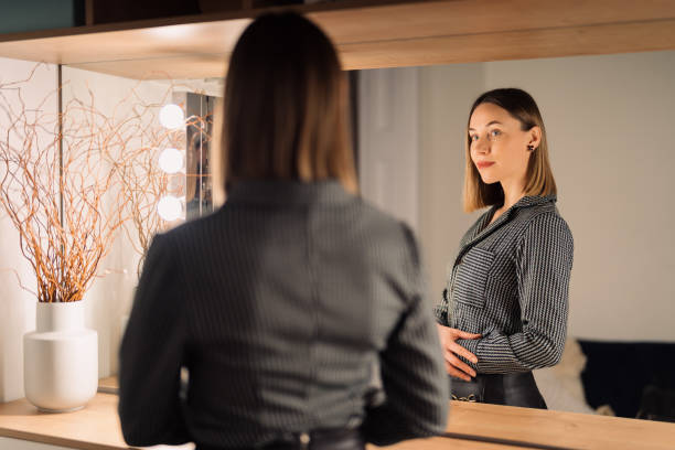 istock Lovely woman looking at her reflection in the mirror 1368641146
