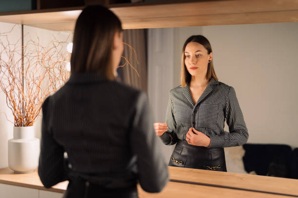 istock Lovely woman looking at her reflection in the mirror 1368641147
