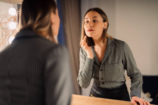 istock Lovely woman looking at her reflection in the mirror 1368641152