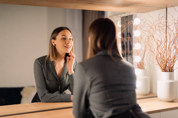 Lovely woman looking at her reflection in the mirror stock photo