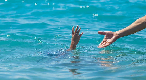 The child is drowning in the water the hand of salvation. Selective focus.