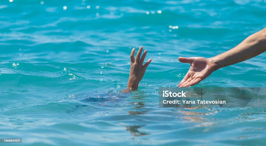 The child is drowning in the water the hand of salvation. Selective focus. The child is drowning in the water the hand of salvation. Selective focus. People. Drowning Stock Photo