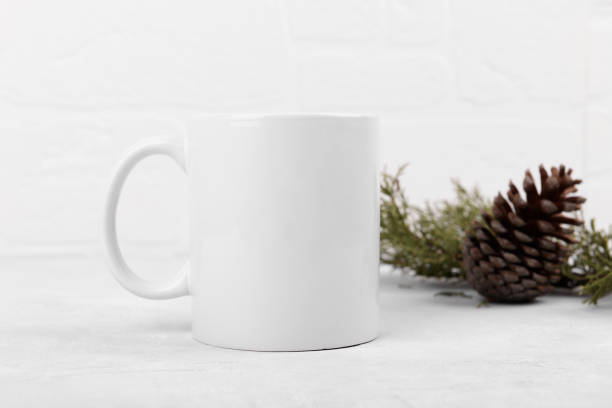 istock White mug mockup with blank copy space. Coffee cup on a light grey background with pine cone and fir branch 1368642949