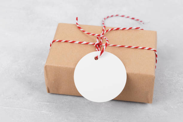 istock Round empty gift tag mockup on gift kraft box on grey background 1368642952