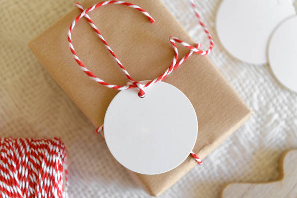 istock Christmas simple blank paper label mockup with string on gift box on knitted beige background 1368642955