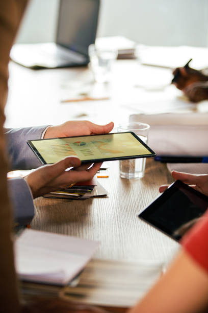 istock Businessman holding a digital tablet, showing data to his colleagues 1368644512