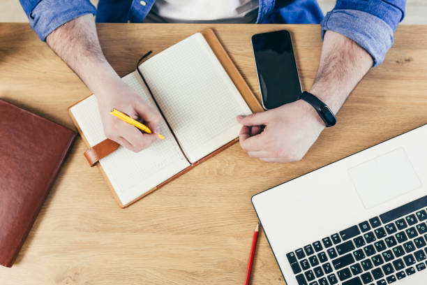 istock hangs young man at home in the kitchen, working on laptop online, talking on the phone, working with documents, making notes, talking video communication, studying, teaching, close up 1368644651