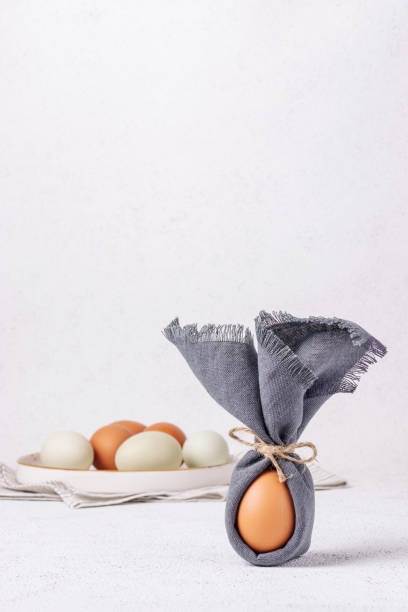 istock Easter egg decorated with a napkin in the shape of a bunny on a white concrete background 1368646026
