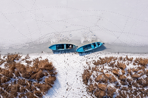 Fishing boats standing on snow-covered lake. Taken via drone. Burdur, Turkey.