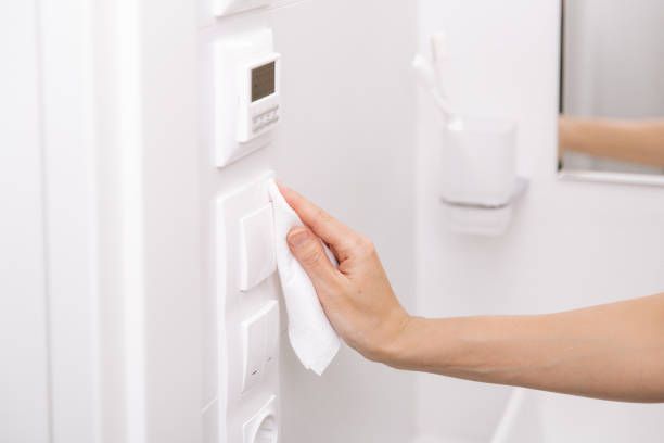 istock Cleaning switches and sockets with a microfiber cloth. Sanitize surfaces prevention in hospital and public spaces against corona virus. Woman hand using wet wipe for cleaning home room door link 1368648012