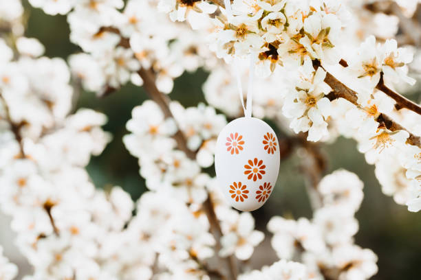 istock Easter egg in beige and brown tones hanging in between almond blossoms on an almond tree 1368650454