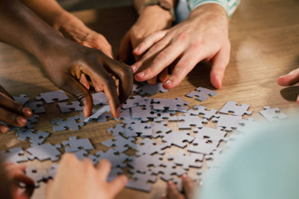 istock Group of people cooperating and solving a jigsaw puzzle together 1368650558
