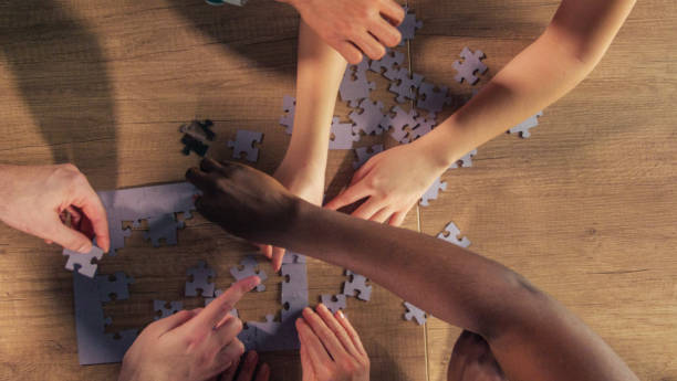 istock People sitting at table, arranging jigsaw puzzle pieces together 1368650567