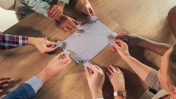 istock Group of people adding final pieces of the jigsaw puzzle together 1368650573