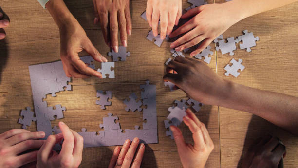 istock Group of unrecognizable people assembling a puzzle together 1368650589