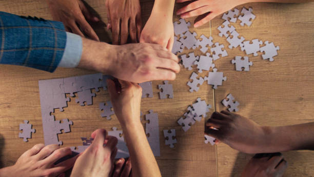 istock Group of diverse friends putting a jigsaw puzzle together 1368650596