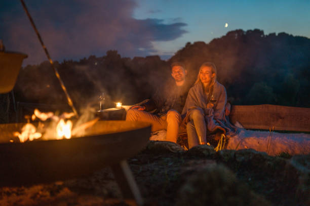 молодая кавказская пара проводит качественное время рядом с капмфайром - log fire стоковые фото и изображения