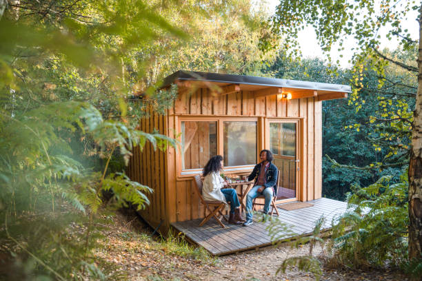 Full length shot of Hispanic couple having coffee on a patio of their glamping cabin.