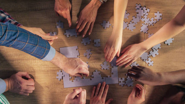 istock Diverse hands arranging jigsaw puzzle pieces together 1368651575