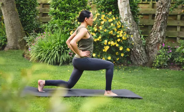 Photo of Shot of a mature woman doing forward lunges while exercising outdoors