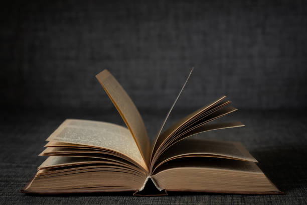 istock Old open book on a dark background close-up 1368663029