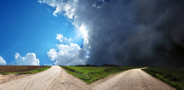 Empty forked road over conceptual dramatic sky stock photo