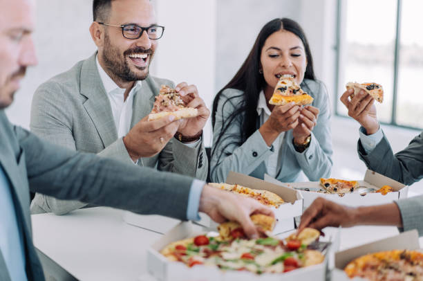 사무실에서 함께 점심 식사를하는 동료. - pizza eating african descent lunch 뉴스 사진 이미지