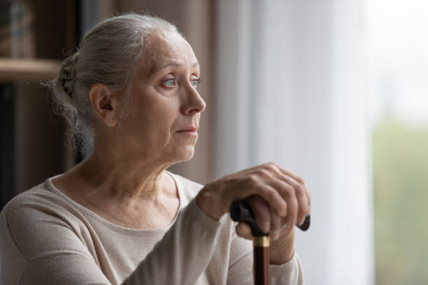 Frustrated middle aged woman with walking disability looking in distance. Head shot frustrated middle aged mature retired woman with walking disability holding hands on wooden stick, looking in distance, feeling lonely at home or suffering from depression, ageing concept. senior adult memory loss stock pictures, royalty-free photos & images