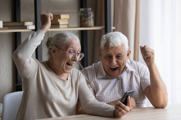 Happy laughing euphoric middle aged couple celebrating success.