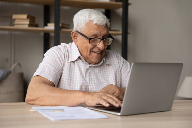 istock Smiling mature man in eyeglasses working on computer. 1368666497