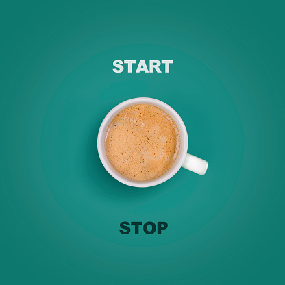 Concept of start/stop button on green background with a coffee mug