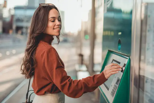 A young woman, a young woman walking down the street and stopped by an ATM to withdraw money for shopping.
