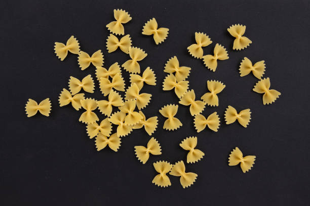 makaron farfalle na czarnym tle, widok z góry - bow tie pasta italian cuisine bow heap zdjęcia i obrazy z banku zdjęć