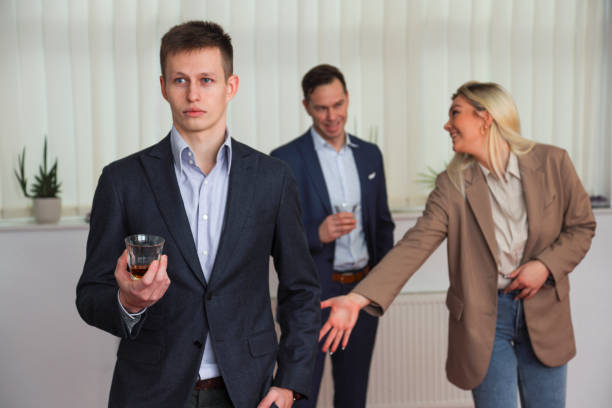 Young woman flirting and trying to put hand on man's buttocks Young businessman on office party with two coworkers in the back having fun of him and woman trying to touch his butt. man touching womans buttock stock pictures, royalty-free photos & images