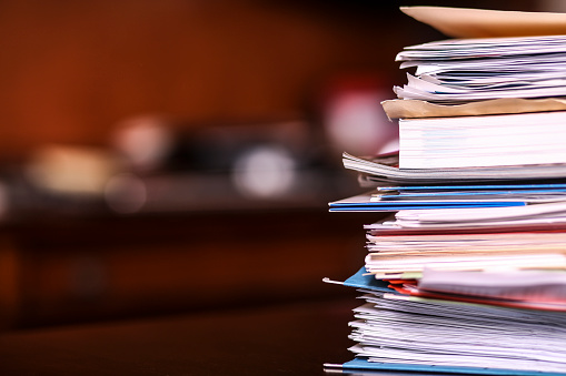 Large stack of bills, data, or paperwork in file folders on business person's desk in office. Home or business. No people.
