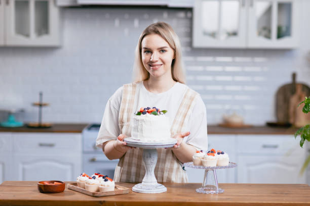 istock Pastry chef confectioner young caucasian woman with cake on kitchen table. 1368681147