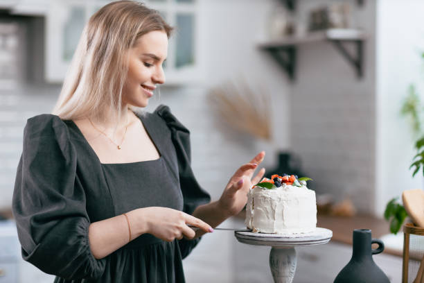 istock Pastry chef confectioner young caucasian woman with cake on kitchen table. 1368681163