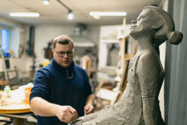 istock Man sculptor creates sculpt bust clay human woman sculpture. Statue craft creation workshop 1368681188