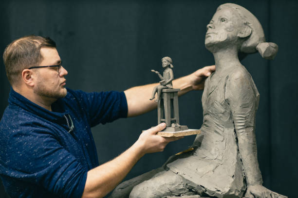 istock Man sculptor creates sculpt bust clay human woman sculpture. Statue craft creation workshop 1368681192