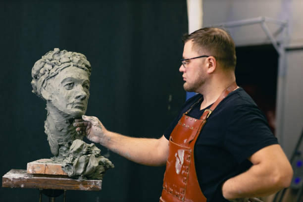 istock Man sculptor creates sculpt bust clay human woman sculpture. Statue craft creation workshop 1368681204