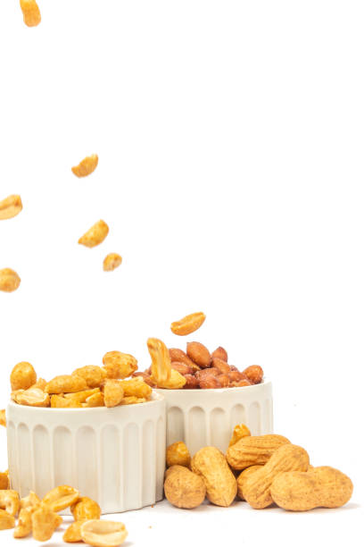 Varieties of peanuts in bowls with peanuts falling on white background Three varieties of peanuts in bowls on the white background, with falling peanuts and front view. vitamin b 3 stock pictures, royalty-free photos & images