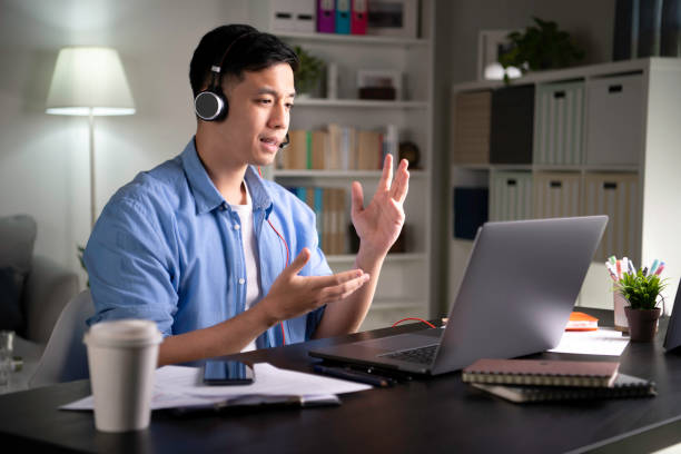 giovane uomo d'affari asiatico che si unisce online in videoconferenza - working at home headset telecommuting computer foto e immagini stock