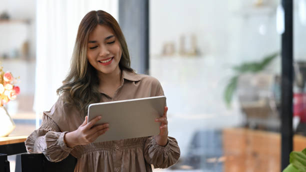 istock Happy young woman sitting in cafe and using digital tablet. 1368709100