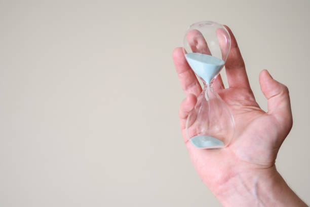 istock Hourglass in the hands of a man on a light background. 1368714004