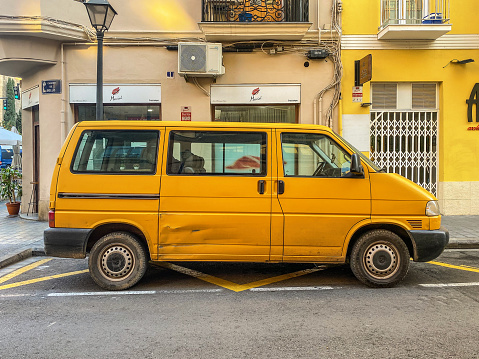 Valencia, Spain - February 3, 2022: Yellow Volkswagen van model Eurovan TDi parked in the street. The german manufacturer produced it from 1990 until 2004