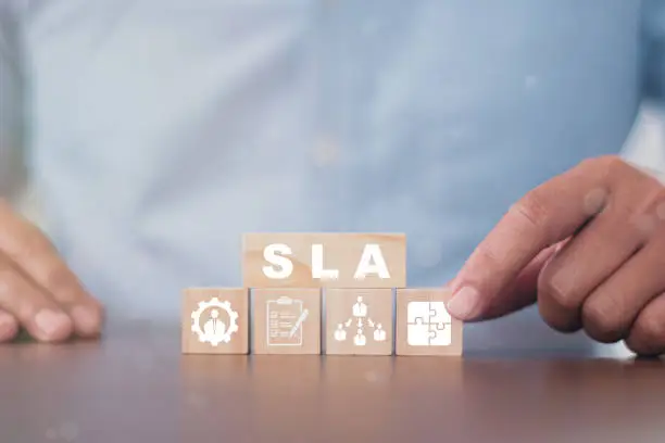 Hand flips wood cube with SLA to customer satisfaction symbols SLA - Service Level Agreement acronym, business concept. Service performance tracking to reduce the uncertainty the customer in process.