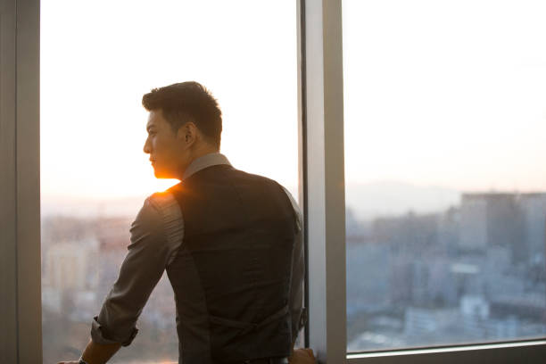 istock Successful Chinese businessman looking out window in his office 1368722520
