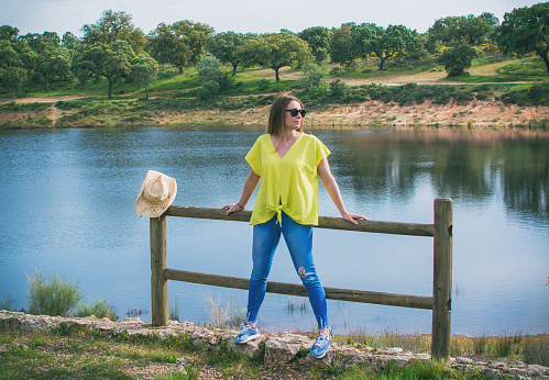 Beautiful Young Woman Enjoying A Nice Sunny Spring Day In A Natural Park. She Has A Cowboy Hat And Is Wearing Sunglasses. Pretty Woman Smiling. Image With Copy Space. People And Nature